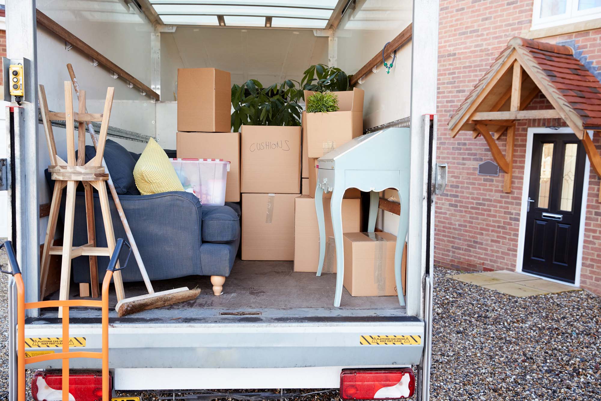 Removal Truck Waiting To Be Unloaded Outside New Home On Moving Day