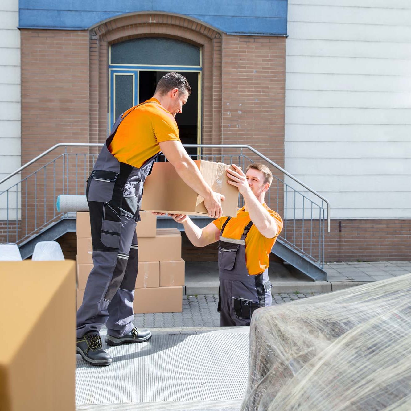 MainHero Young Movers Unloading The Boxes In The Van. Young Male Movers Unloading The Cardboard Boxes In The Van Outside The House