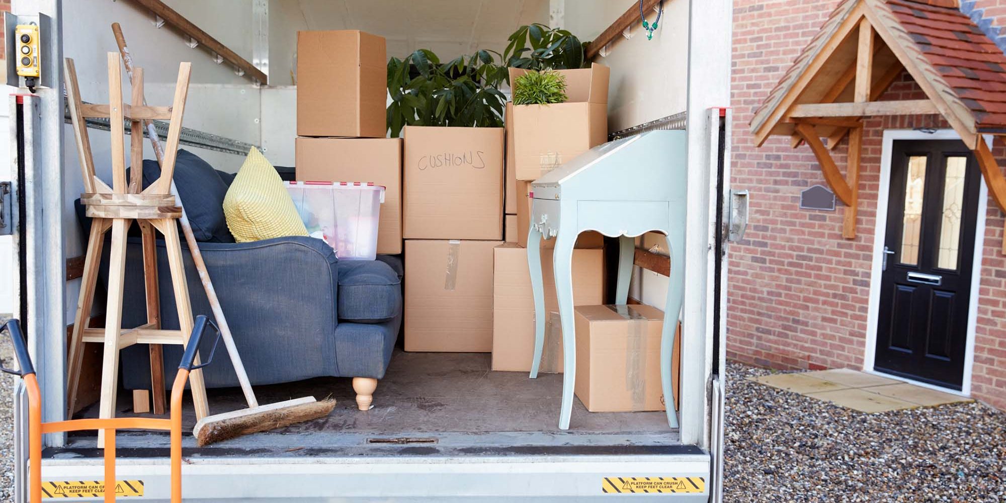 Removal Truck Waiting To Be Unloaded Outside New Home On Moving Day